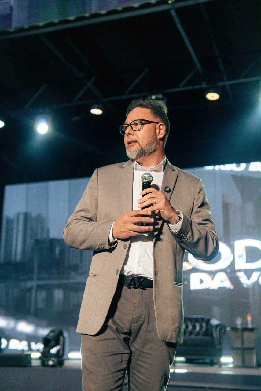 Hideki Kouketsu palestrando no palco, com microfone na mão